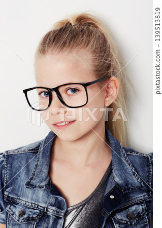Child, portrait and cool fashion glasses in studio, frame and confident by white background. Female person, girl and casual clothing or style by backdrop, kid and denim jacket pride for eyesight test 139513819