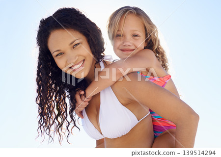 Happy mother, child and piggyback in sun at beach for bonding, vacation or outdoor holiday weekend together. Portrait of mom, kid or daughter smile for love, support or summer on blue sky background Happy mother, child and piggyback in sun at beach for bonding, vacation or outdoor holiday weekend together. Portrait of mom, kid or daughter smile for love, support or summer on blue sky background 139514294