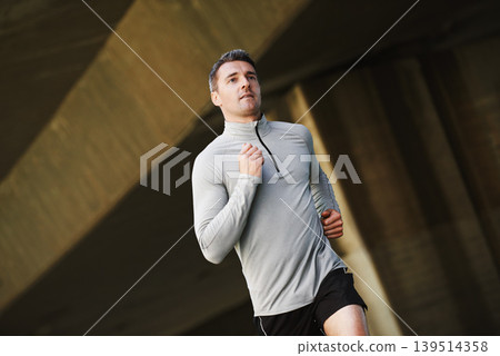 Man, runner and wellness on street in outdoors, cardio and exercise or training for marathon. Male person, athlete and workout by city background, sportswear and performance challenge by bridge 139514358