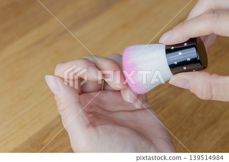 一位女士正在用除塵刷清除指甲縫裡的灰塵。 139514984