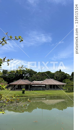A scene of traditional Okinawan gardens and old houses with red tile roofs reflected on the water's surface. A scene of traditional Okinawan gardens and old houses with red tile roofs reflected on the water's surface. 139515104