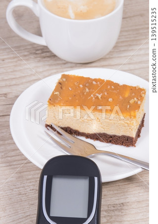 Glucometer for measuring sugar level, sweet cheesecake and cup of coffee with milk Glucometer for measuring sugar level, sweet cheesecake and cup of coffee with milk 139515235