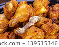 Closeup of Hot and Spicy Grilled Chicken Drumettes Piled in a Black Tray, Featuring One Cleaned Bone from an Eaten Piece, Glazed with Savory Spicy Sauce and Golden Color 139515346