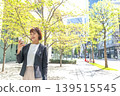 A businesswoman walking through the streets of Marunouchi, holding her smartphone. 139515545