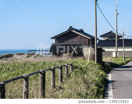 在秋田縣,日本海沿岸排列著傳統的瓦頂房屋;這是一個坐落在俯瞰大海的小山上的漁村。 在秋田縣,日本海沿岸排列著傳統的瓦頂房屋;這是一個坐落在俯瞰大海的小山上的漁村。 139515922