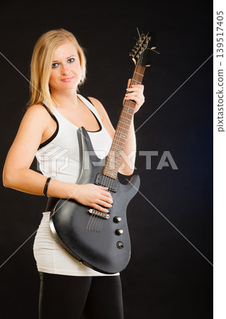 Blonde woman holding electric guitar, black background Blonde woman holding electric guitar, black background 139517405