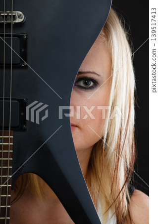 Blonde woman holding electric guitar, black background Blonde woman holding electric guitar, black background 139517413