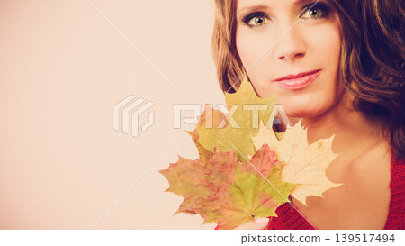Pretty autumnal girl with maple leaves in hand Pretty autumnal girl with maple leaves in hand 139517494