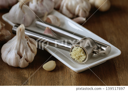 Garlic bulbs and garlic press on a wooden table. 139517897
