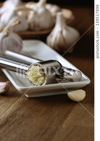 Garlic bulbs and garlic press on a wooden table. Garlic bulbs and garlic press on a wooden table. 139517898