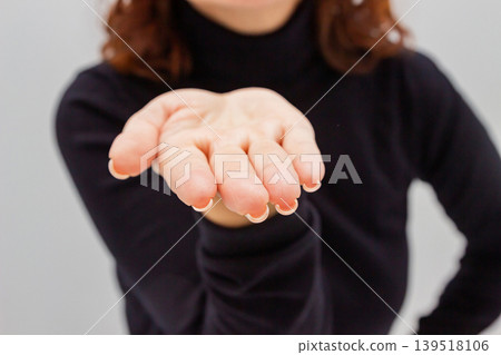 Woman holding out her open hand with palm facing up. Gesture of showing, presenting or offering something. Conceptual studio shot representing support, giving, receipt or charity. 139518106