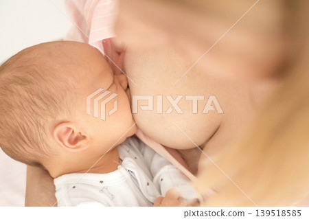 A newborn baby during breastfeeding in close-up. Establishing lactation A newborn baby during breastfeeding in close-up. Establishing lactation 139518585