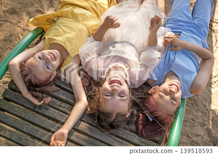 Beautiful happy Girls are lying on sun beds on the beach by the sea. View from above Beautiful happy Girls are lying on sun beds on the beach by the sea. View from above 139518593