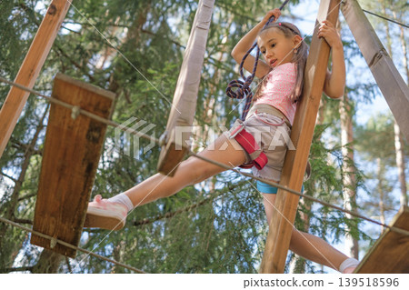 The child overcomes obstacles by stepping on suspended steps located at a distance. Extreme sports. Rope entertainment town in the park The child overcomes obstacles by stepping on suspended steps located at a distance. Extreme sports. Rope entertainment town in the park 139518596