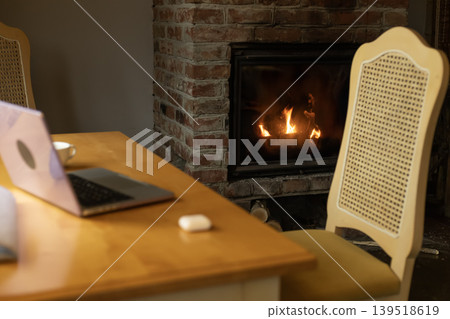 Fireplace laptop and chair in cozy home interior Fireplace laptop and chair in cozy home interior 139518619