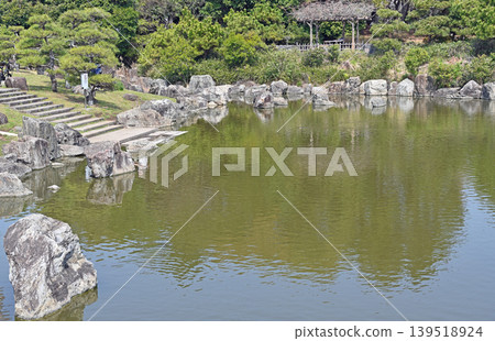 A charming Japanese garden in the heart of the city: A tranquil landscape woven from traditional stone arrangements and a pond, symbolizing classic beauty. A charming Japanese garden in the heart of the city: A tranquil landscape woven from traditional stone arrangements and a pond, symbolizing classic beauty. 139518924