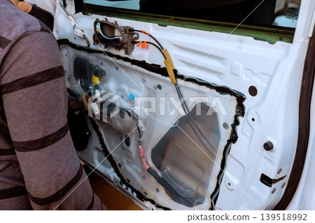 Person works on car door repair inside garage with tools equipment around 139518992