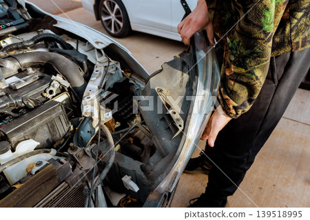 Worker works on fixing car headlight during garage service 139518995