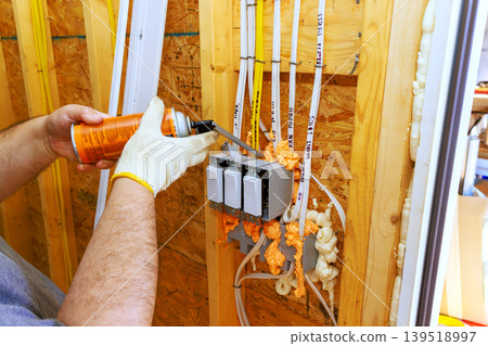 Electrician works on wiring fire proof sealant insulation in construction site Electrician works on wiring fire proof sealant insulation in construction site 139518997