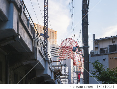 透過城市縫隙,可以看到一座紅色摩天輪和高架橋。 透過城市縫隙,可以看到一座紅色摩天輪和高架橋。 139519081