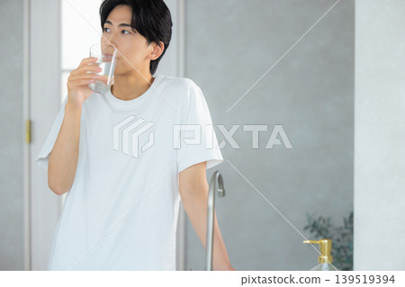 一名男子正在用玻璃杯喝水。 一名男子正在用玻璃杯喝水。 139519394