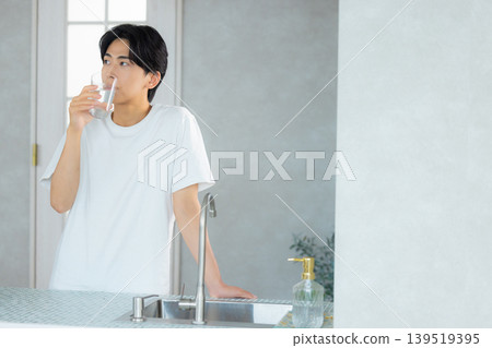 一名男子正在用玻璃杯喝水。 一名男子正在用玻璃杯喝水。 139519395