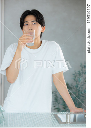 一名男子正在用玻璃杯喝水。 一名男子正在用玻璃杯喝水。 139519397