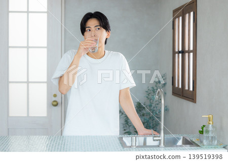 一名男子正在用玻璃杯喝水。 一名男子正在用玻璃杯喝水。 139519398