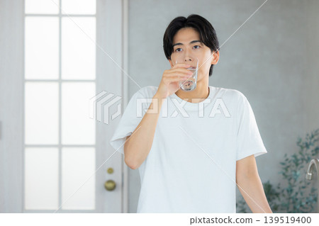 一名男子正在用玻璃杯喝水。 一名男子正在用玻璃杯喝水。 139519400