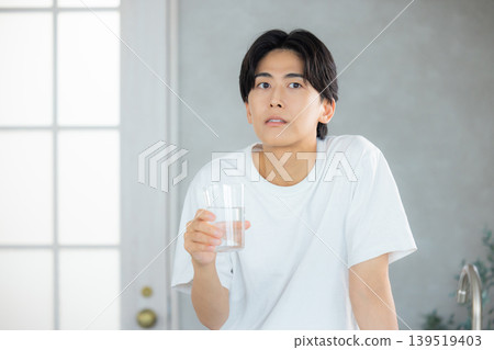 一名男子正在用玻璃杯喝水。 一名男子正在用玻璃杯喝水。 139519403