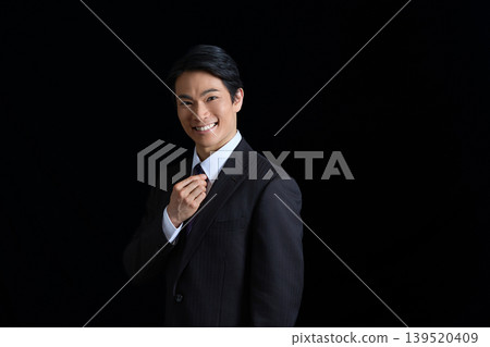 Portrait of a smiling young businessman against a black background Portrait of a smiling young businessman against a black background 139520409
