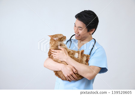 Portrait of a smiling male veterinarian holding a cat, against a white background. Portrait of a smiling male veterinarian holding a cat, against a white background. 139520605