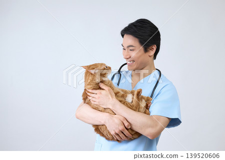 Portrait of a smiling male veterinarian holding a cat, against a white background. Portrait of a smiling male veterinarian holding a cat, against a white background. 139520606