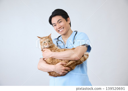 Portrait of a smiling male veterinarian holding a cat, against a white background. 139520691