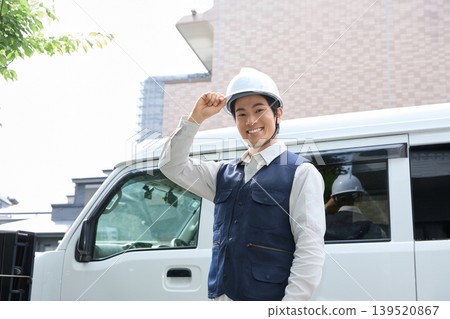 A male worker smiles while holding a helmet. A male worker smiles while holding a helmet. 139520867