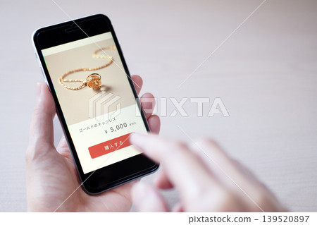 一張照片，展示了一個人使用智慧型手機在線購買商品（螢幕設計為原創）。 139520897