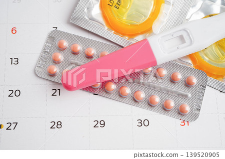 Pregnancy test with birth control pills and condom for female on calendar, ovulation day. Pregnancy test with birth control pills and condom for female on calendar, ovulation day. 139520905