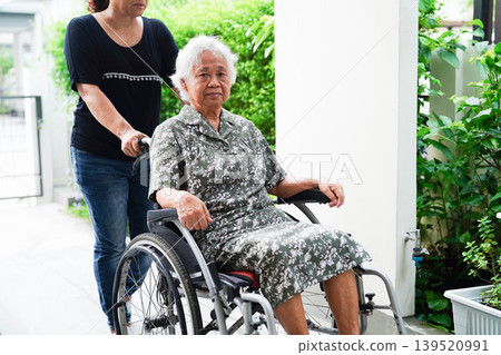 Caregiver help Asian elderly woman disability patient sitting on wheelchair in hospital. Caregiver help Asian elderly woman disability patient sitting on wheelchair in hospital. 139520991