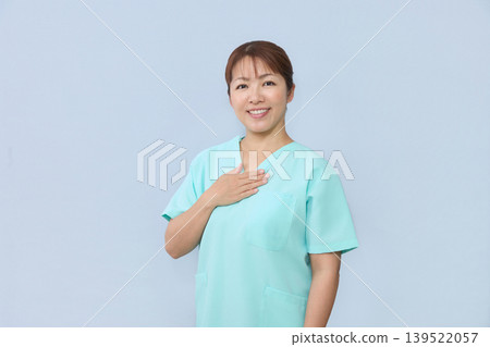 一名女醫護人員面帶微笑，將手放在胸口。 139522057
