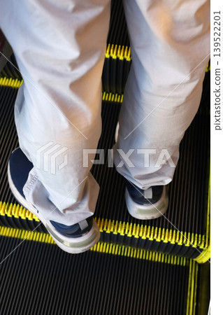 Person standing on escalator step Person standing on escalator step 139522201
