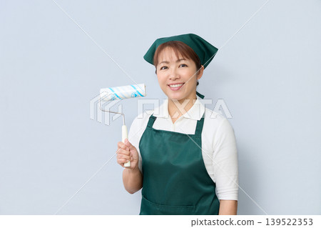 A smiling house cleaning staff member holding a cleaning roller. A smiling house cleaning staff member holding a cleaning roller. 139522353