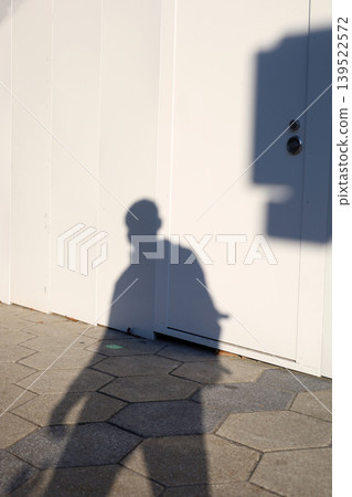Shadow of person walking beside white wall Shadow of person walking beside white wall 139522572