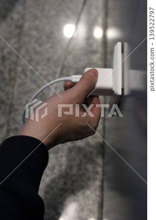 Hand plugging charger into wall socket Hand plugging charger into wall socket 139522797