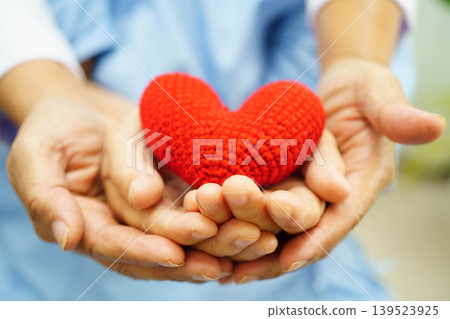 Asian elder senior woman patient holding red heart in hospital. Asian elder senior woman patient holding red heart in hospital. 139523925