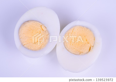 Eggs on lavender. Closeup of halved eggs with vibrant yolks on lavender setting. Detailed view of cut boiled eggs featuring vivid yolks against soothing lavender surface Eggs on lavender. Closeup of halved eggs with vibrant yolks on lavender setting. Detailed view of cut boiled eggs featuring vivid yolks against soothing lavender surface 139523972