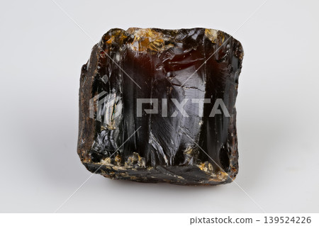 Glossy dark resin with reflections. Resin sample displaying cubic form and glassy surfaces. Dark resin piece with amber reflections and internal crystal details Glossy dark resin with reflections. Resin sample displaying cubic form and glassy surfaces. Dark resin piece with amber reflections and internal crystal details 139524226