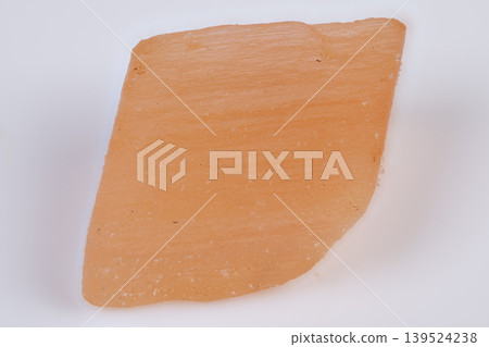 Photograph showing layered structure and translucency of mineral fragment. Image demonstrating layered construction and seethrough quality of mineral sample with red hue Photograph showing layered structure and translucency of mineral fragment. Image demonstrating layered construction and seethrough quality of mineral sample with red hue 139524238