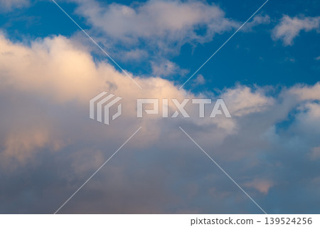 Wide blue sky dotted with sunset clouds, cool tones balanced by warm highlights, clean airy composition, peaceful evening vibe suited for backgrounds and wellness campaigns 139524256