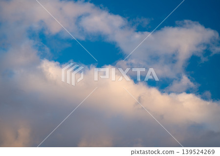 Puffy clouds catching warm sunset light, edges kissed by golden hues, deep blue backdrop, textured shadows, calm dusk mood ideal for travel and lifestyle visuals Puffy clouds catching warm sunset light, edges kissed by golden hues, deep blue backdrop, textured shadows, calm dusk mood ideal for travel and lifestyle visuals 139524269