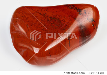 Polished jasper stone with black spots. Tumbled red jasper with glossy surface and dark flecks. Refined red jasper mineral featuring smooth contours and black specks for design Polished jasper stone with black spots. Tumbled red jasper with glossy surface and dark flecks. Refined red jasper mineral featuring smooth contours and black specks for design 139524301